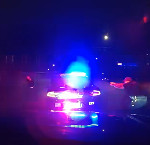 A screen shot of a video that shows an officer trading shots next to his squad car with a homicide suspect. 